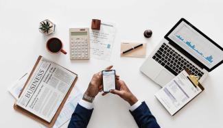 Phone, clipboard, pen and paper on a desk.