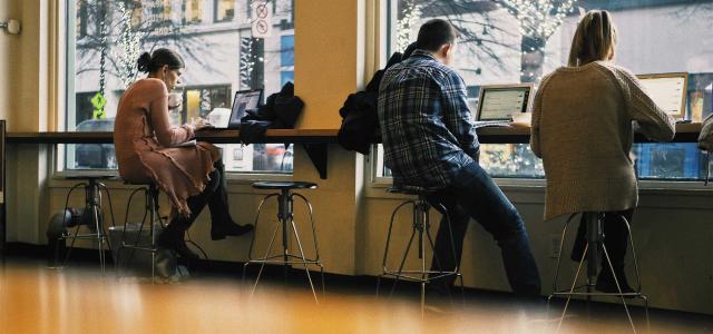 Millennials on laptops in coffee shop.