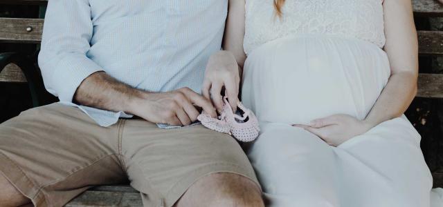 Man and pregnant wife sitting on bench.